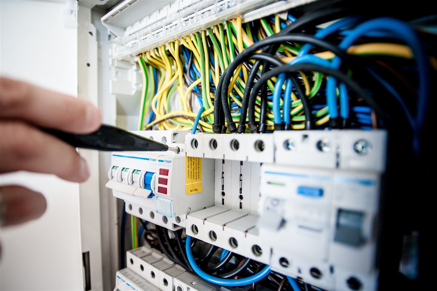 Electrician working inside a consumer unit, connecting circuit breakers